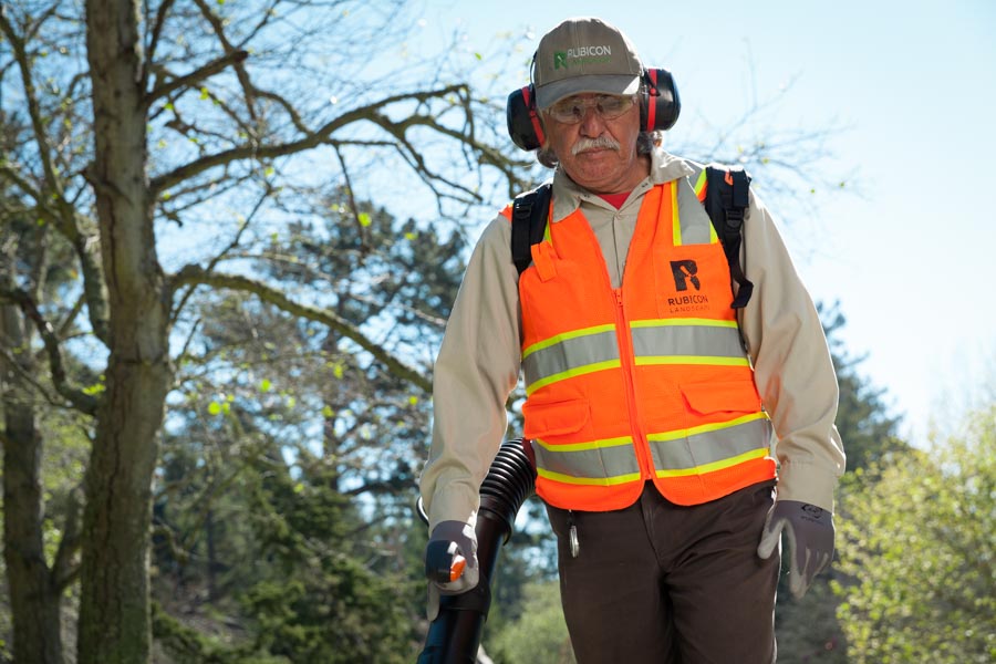Rubicon crew member clearing a park path with a backpack blower