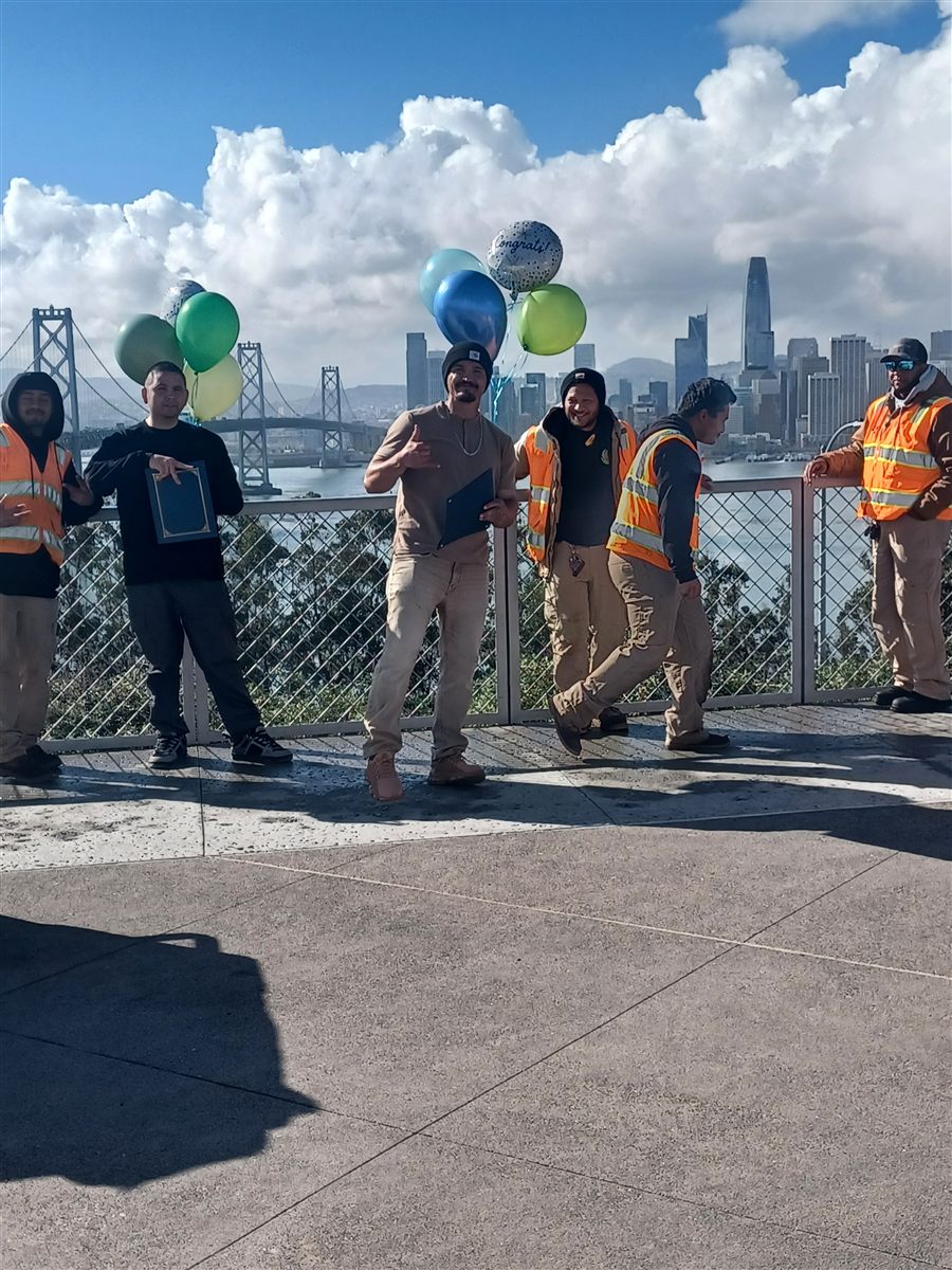 Rubicon crew and trainees celebrating a graduation with balloons and the San Francisco skyline behind them
